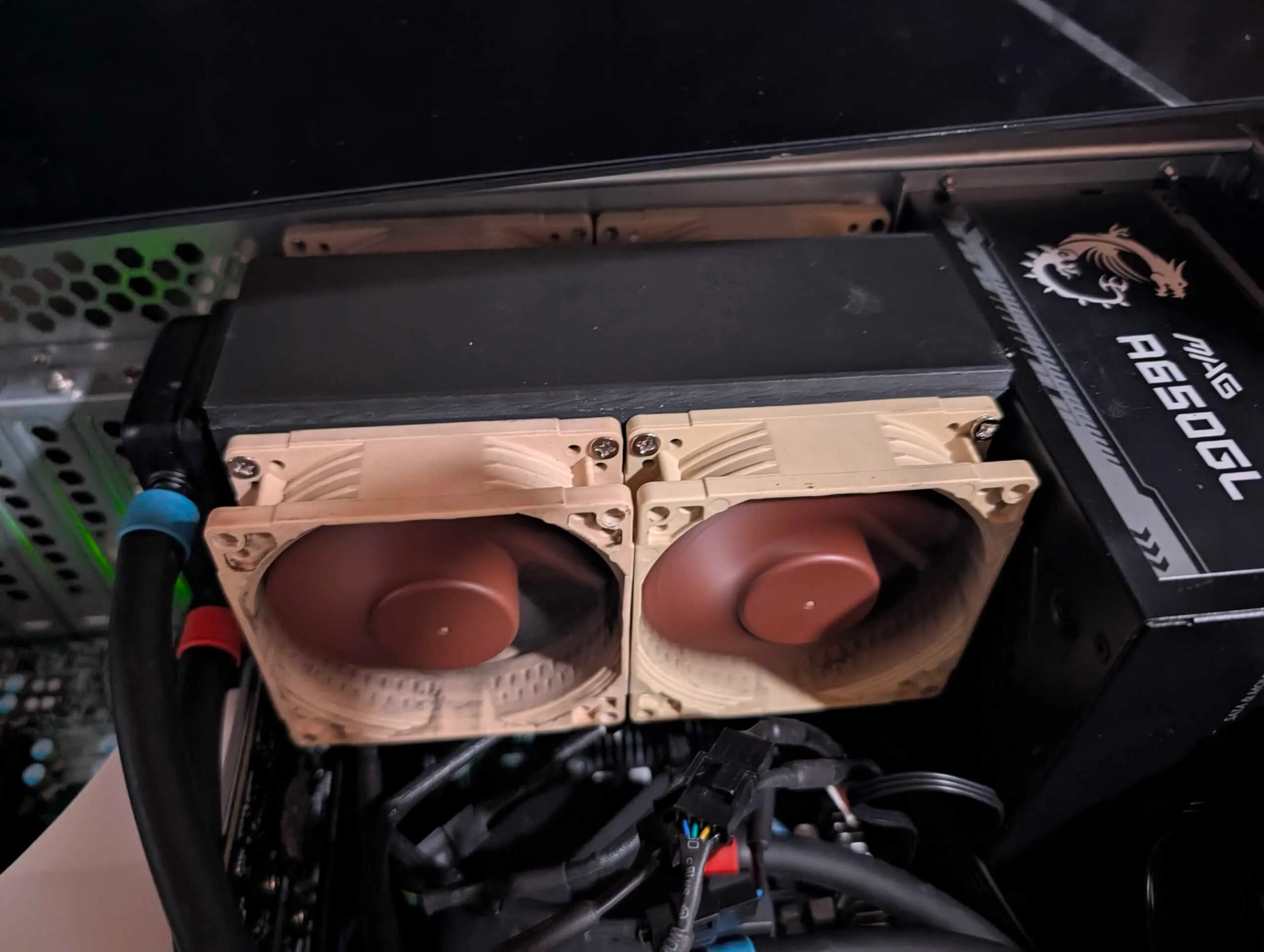 Small AIO radiator sandwiched in the printed bracket with Noctua 80mm fans, next to an MSI MAG A650GL power supply